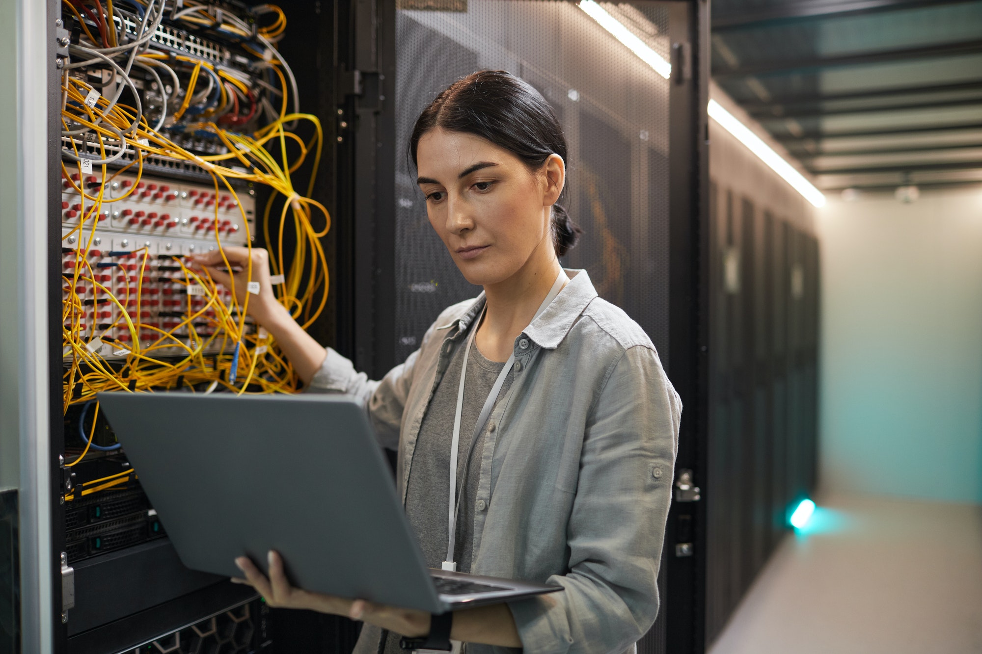Female Network Technician Inspecting Servers in Data Center